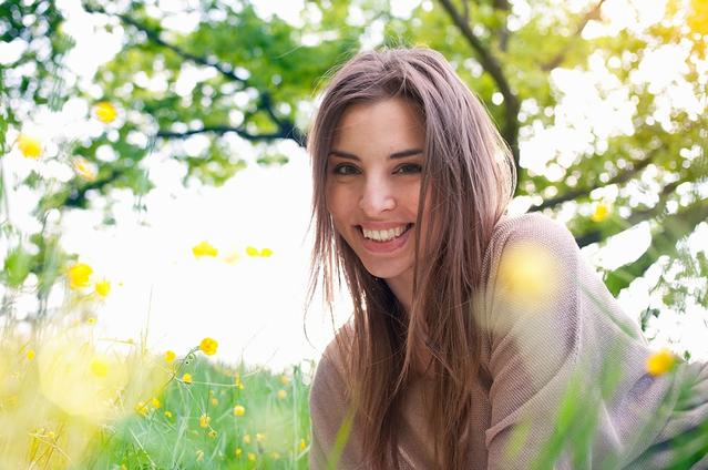 אישה על הדשא מחייכת כאשר השמש מאירה ברקע